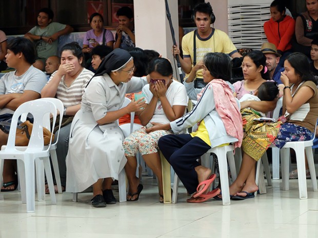 A nun comforts the family of one of the victims.