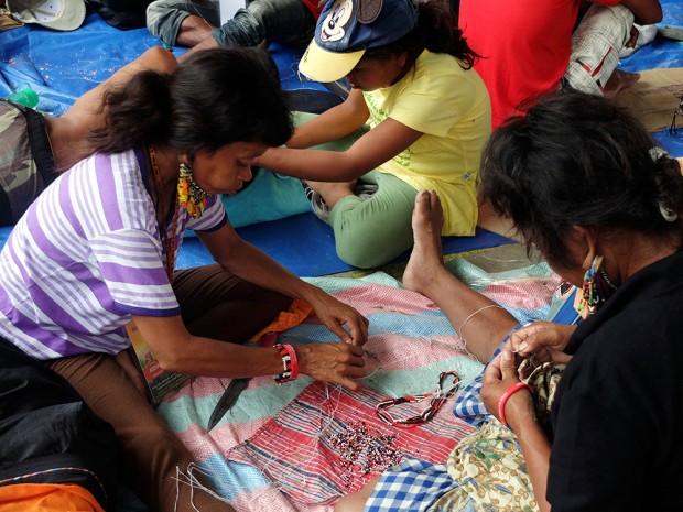 Women, men and children take part in bead-making sessions as much as they delight in wearing them.  To the right is a Manobo male wearing cascading bead earrings anchored by wooden pegs.